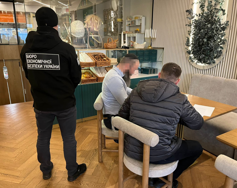 Приміщення кафе. Два детективи БЕБ вручають повідомлення про підозру фігуранту справи.
