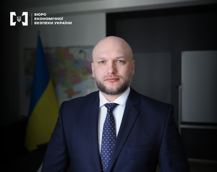 Директор БЕБ Олександр Цивінський. Портретне фото в кабінеті. На затемненому тлі прапор та карта України.