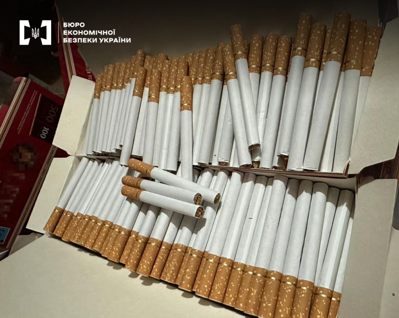 Великим планом сигарети з помаранчевим фільтром щільно складені у відкритій картонній коробці.