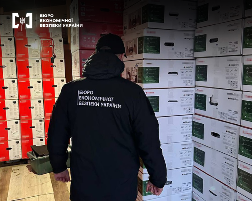 Детектив БЕБ оглядає складське приміщення вщент заповнене складеними одну на одну картонними коробками з побутовою технікою