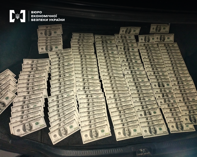 Підроблені банкноти номіналом 100 доларів США розкладені у відкритому багажнику автомобіля