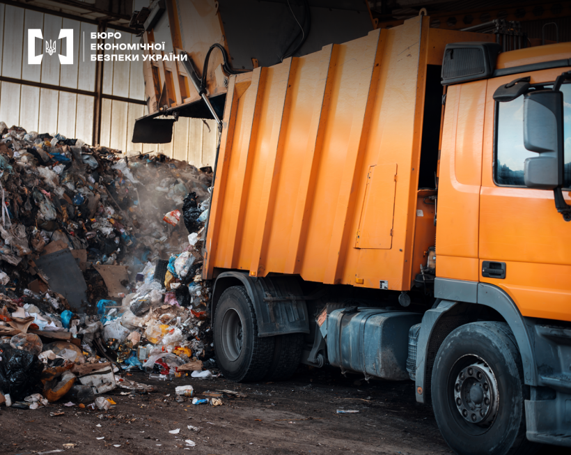 Помаранчевий сміттєвоз вивантажує сміття на звалище