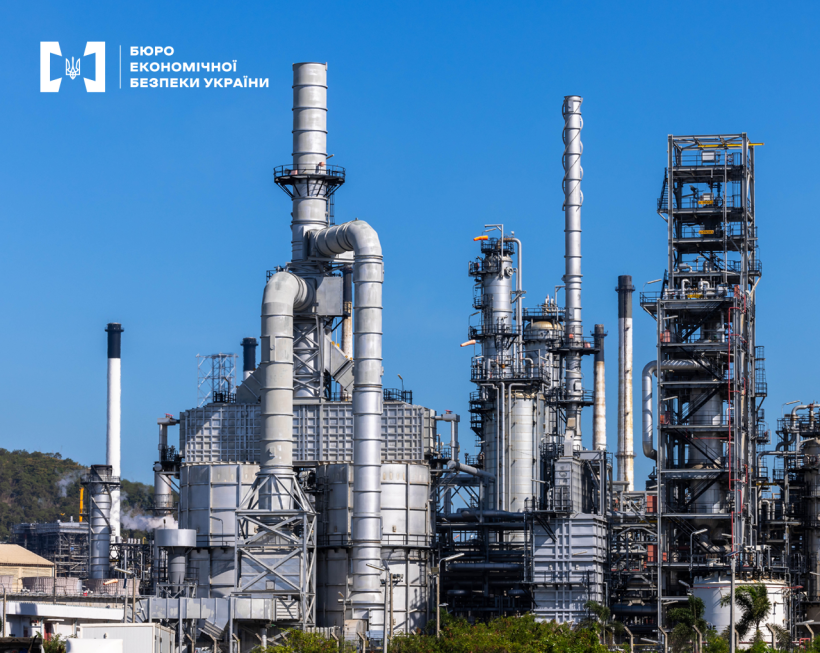Нафтопереробний завод із системою труб, колон та димарів на тлі ясного блакитного неба