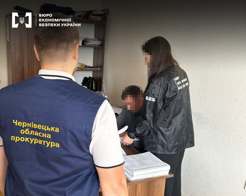 Детектив БЕБ повідомляє про підозру фігуранту справи у робочому кабінеті. Поруч стоїть працівник Чернівецької обласної прокуратури.