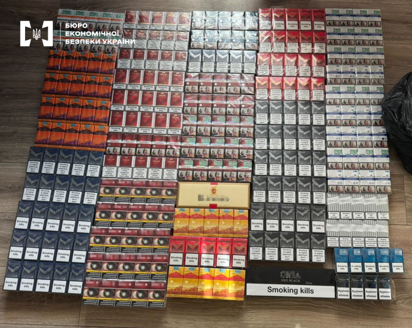 У фокусі сотні пачок сигарет у різнокольорових упаковках, викладених за видами у формі квадрата.  На деяких маркування про шкоду паління.