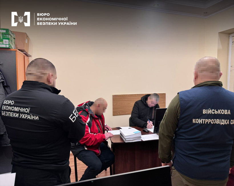 Офісне приміщення. Працівники БЕБ та Департаменту військової контррозвідки СБУ вручають підозру фігурантам справи. Обличчя заблюрені.