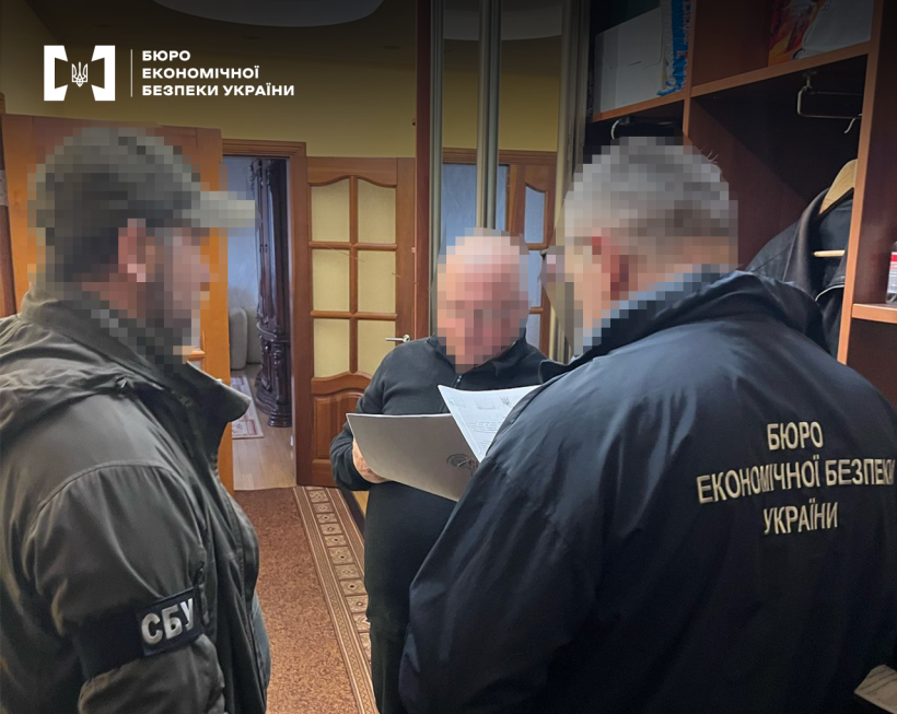 Житлове приміщення. Співробітники БЕБ та СБУ оголошують підозру фігуранту справи. Обличчя заблюрено.