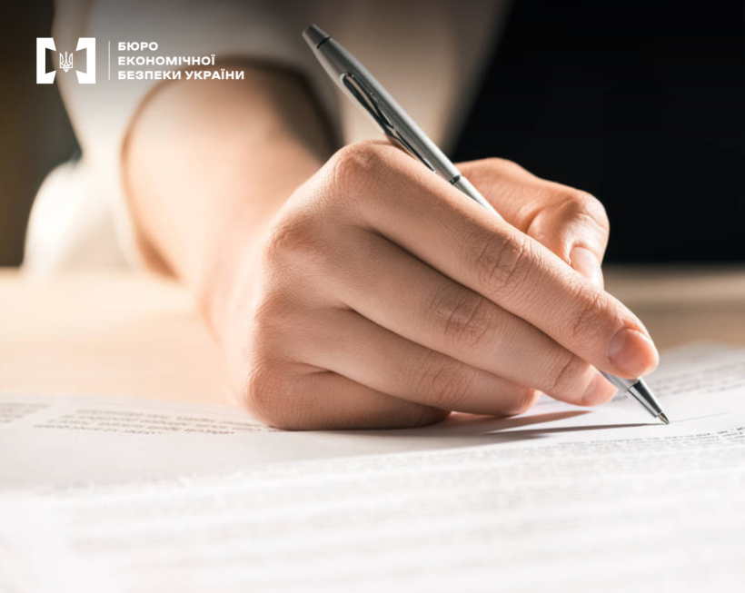 A close-up of a person's hand writing with a silver pen on a clean paper/document