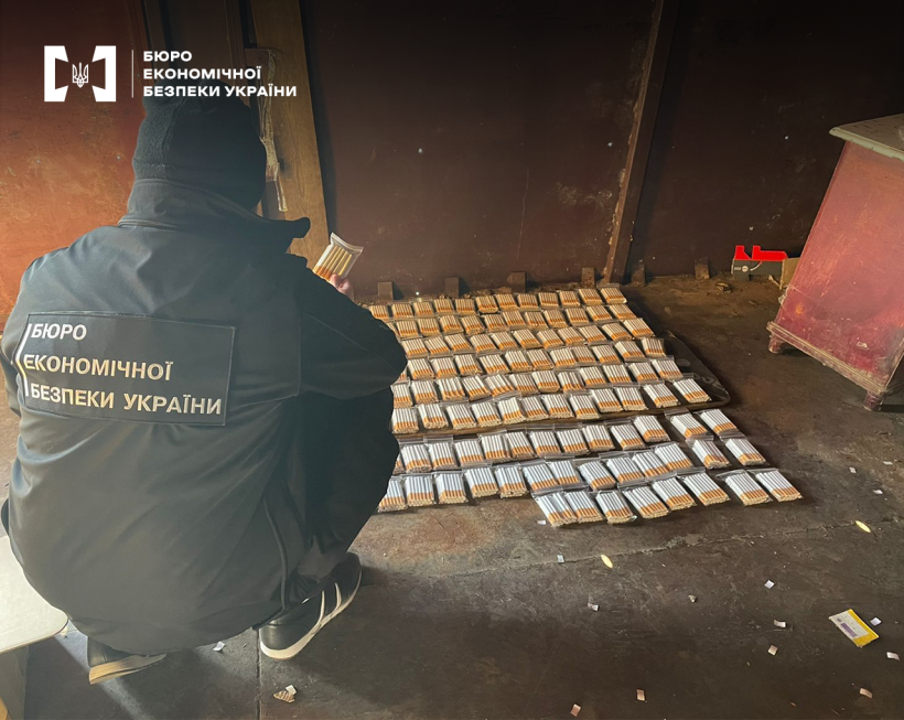 Детектив БЕБ оглядає велику кількість сигарет у зіп-пакетах, розкладених на підлозі