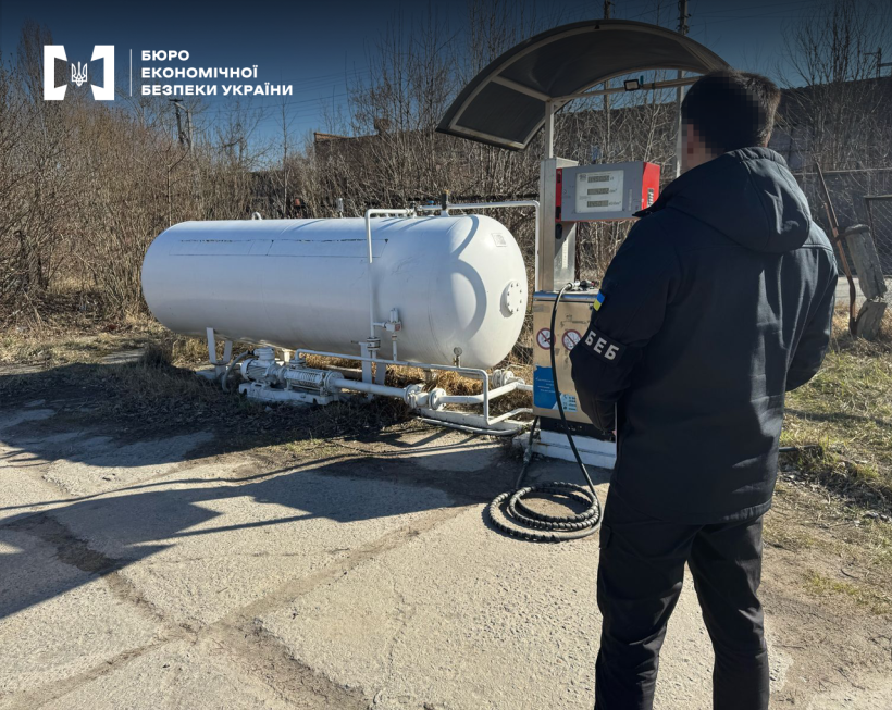 Детектив БЕБ оглядає модуль для зберігання та реалізації газу із заправною колонкою. На фоні занедбана територія АЗС.