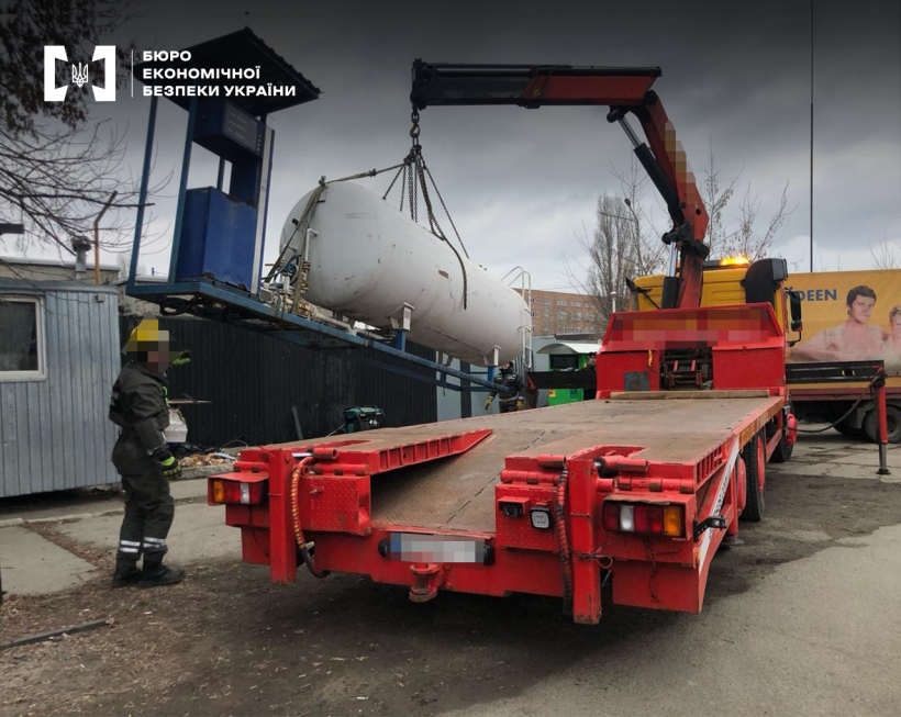Вилучення обладнання та пального з нелегальної АЗС. Автокран завантажує паливно-роздавальну колонку та резервуар для пального на трал для переміщення