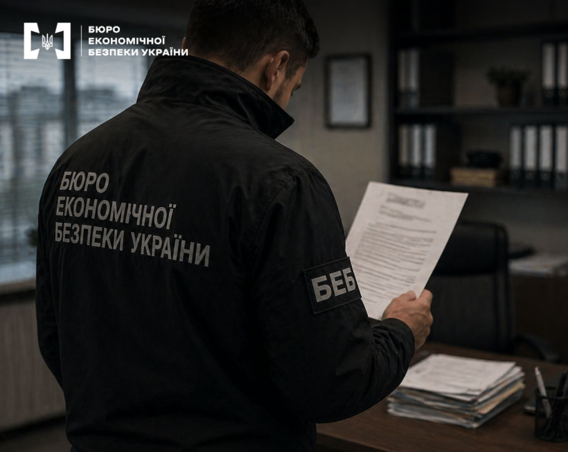Детектив БЕБ вивчає документи в робочому кабінеті