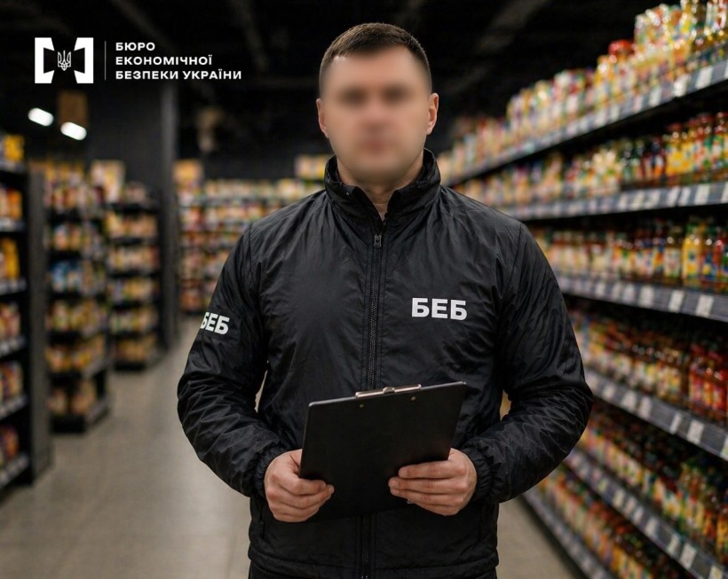 Детектив БЕБ з планшетом у руках на тлі торговельного залу серед довгих стелажів із продуктами харчування