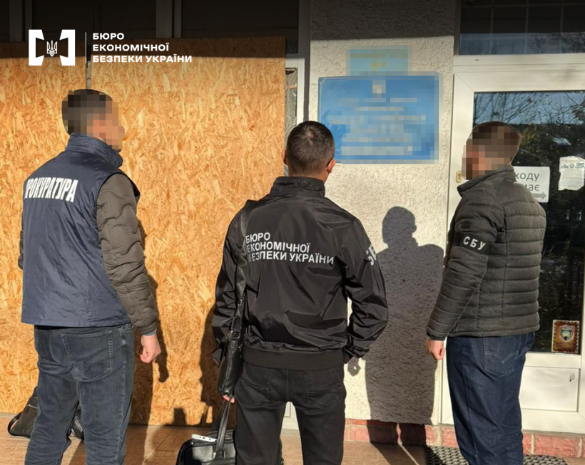 Правоохоронці БЕБ, Прокуратури та СБУ перед входом до адмінбудівлі. На фасаді синя вивіска, назву підприємства заблюрено