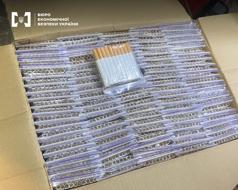 Вигляд зверху на ящик заповнений сигаретами у прозорих зіп-пакетах.  Один пакет лежить поверх інших для демонстрації вмісту.