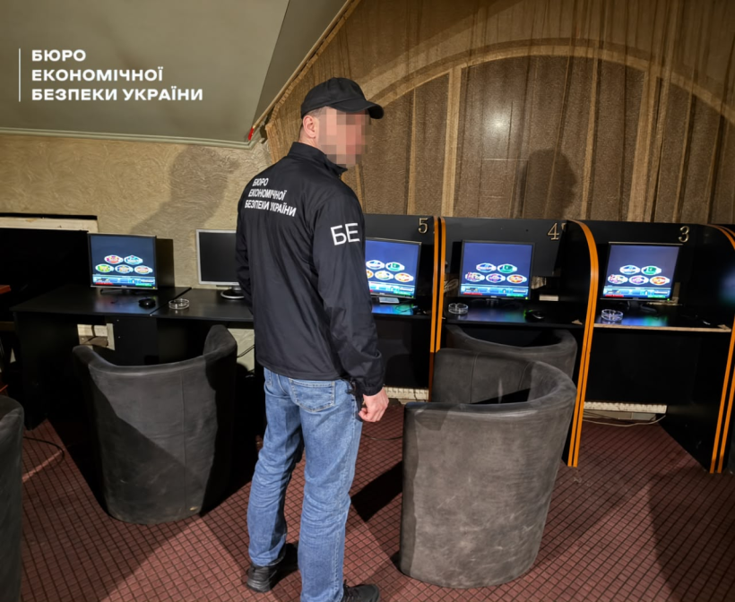 A ESBU detective in a hall with computer simulations of slot machines on the screens and round chairs.