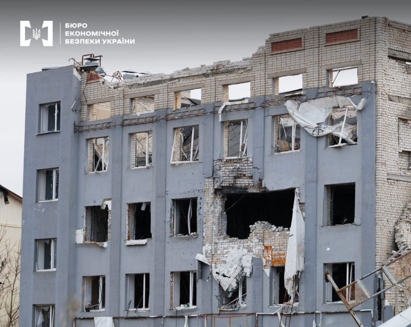 Багатоповерхівка з наслідками обстрілу: вибиті вікна й рами, обвалена покрівля та внутрішні конструкції. На фасаді — велика пробоїна.