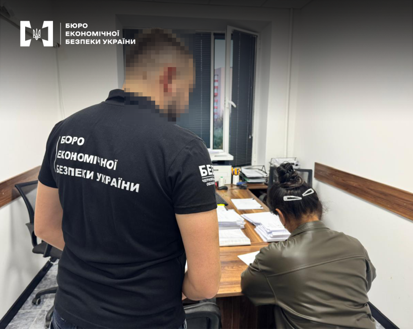 An employee of the ESBU in a corporate T-shirt watches a woman working with documents at an office desk