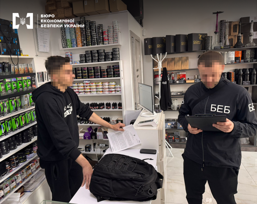 Магазин з продажу тютюнової продукції та супутніх товарів. Продавець за прилавком. Детектив БЕБ зачитує ухвалу суду на обшук.