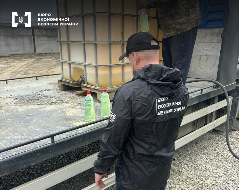 Детектив БЕБ відбирає зразки палива для проведення експертизи. На платформі напівпричепа вантажівки єврокуб для міні АЗС, ПЕТ пляшки з рідиною, шланг