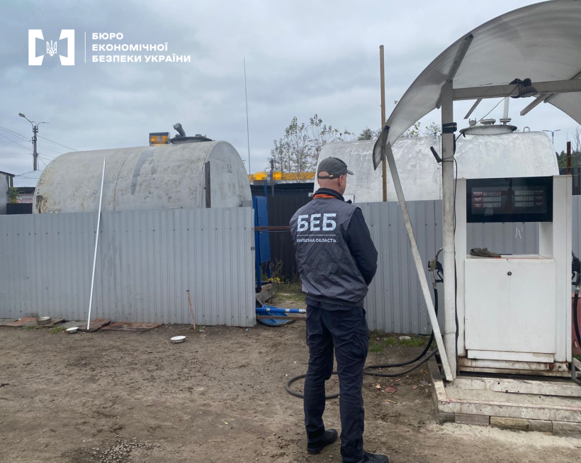 Територія нелегальної АЗС. Детектив БЕБ оглядає стару заправну колонку та металеві ємності для палива