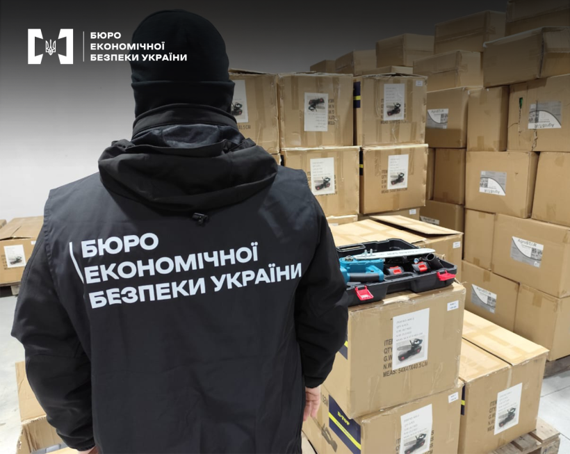 Детектив БЕБ оглядає склад. Навколо одна на одній картонні коробки з електроінструментом. На коробці у відкритій пластиковій валізі ручна пила.