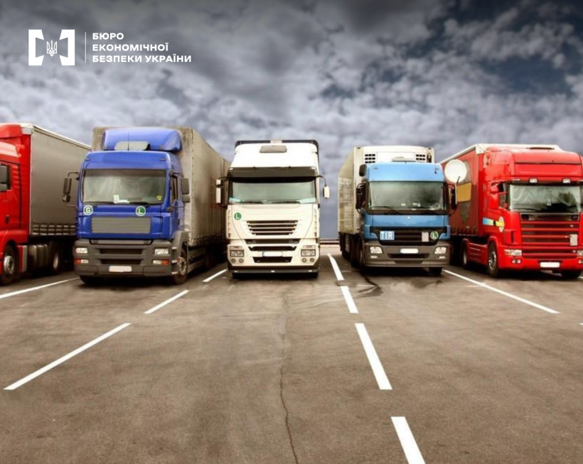 У кадрі стоять п'ять великогабаритних тягачів різних марок та кольорів: червоного, синього, білого та світло-блакитного. На фоні похмуре небо.