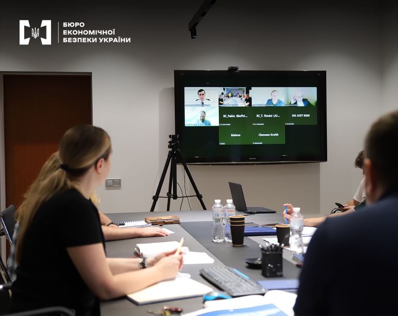 Hybrid-format discussion: some participants are in the conference room, others are connected via video call on a large screen