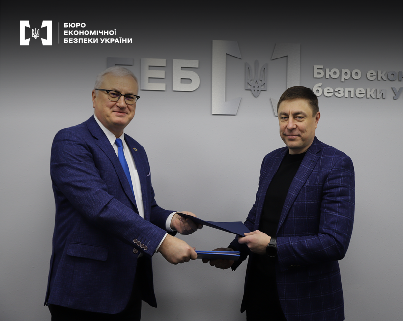 В. о. Директора БЕБ Сергій Перхун та Голова Місії EUBAM Славомір Піхор обмінюються підписаними документами в синіх папках.