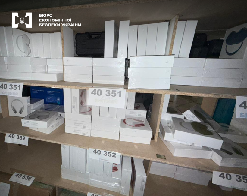 Велика кількість навушників у білих коробках на дерев’яних стелажах. На папірцях, що наклеєні на полиці, вказано номер та колір.
