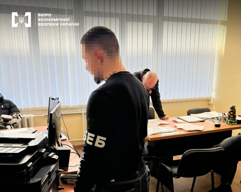Офісне приміщення. Працівник БЕБ вивчає документи розкладені на столі, інший оглядає комп’ютерну техніку