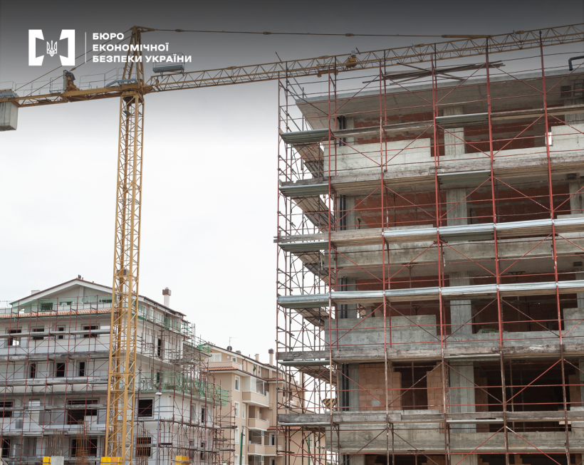 Багатоповерхові будинки на різних етапах готовності. Навколо них встановлені риштування. Між ними будівельний кран.