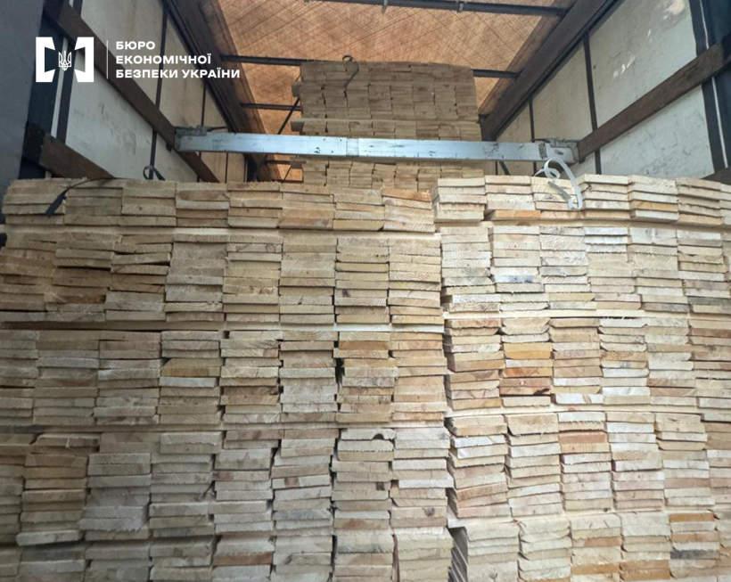 Великим планом необроблені дошки складені штабелями у причепі вантажівки