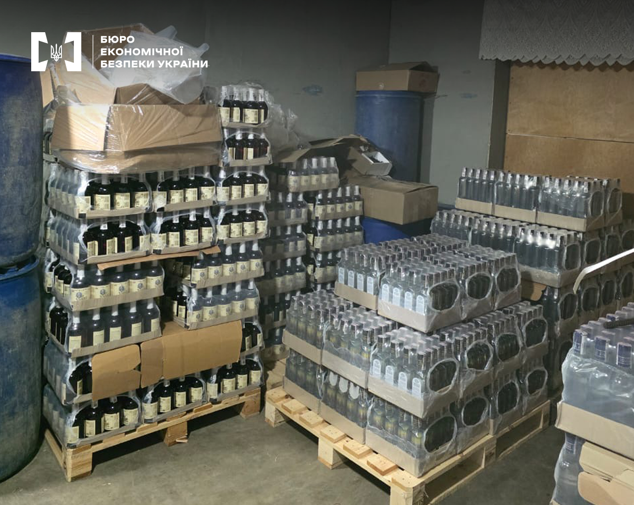 Склад незаконно виготовленого алкоголю. Пляшки, запаковані у термозбіжну плівку та складені у високі стоси на палетах.