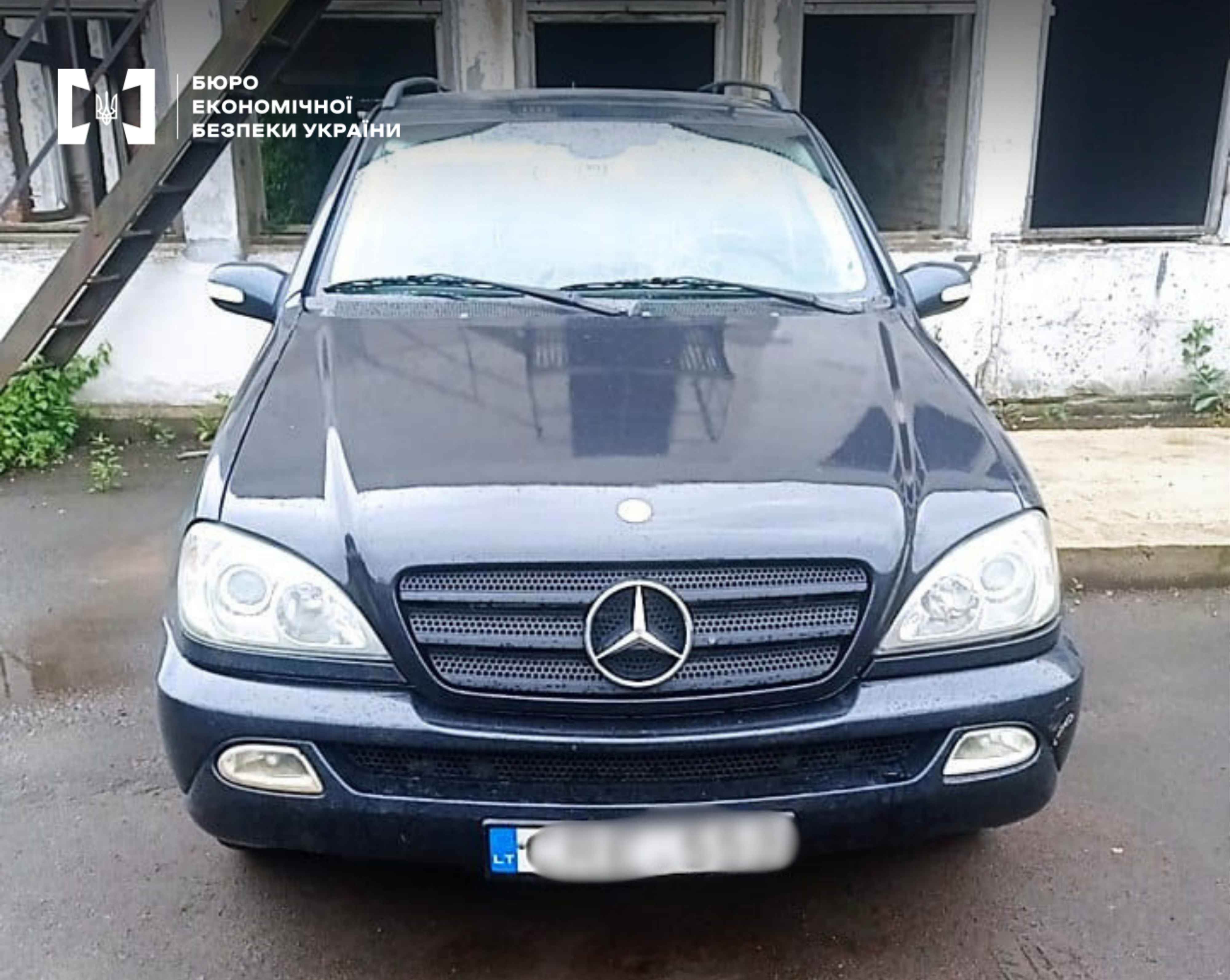 A Mercedes-Benz SUV with a blurred license plate against the background of a building.
