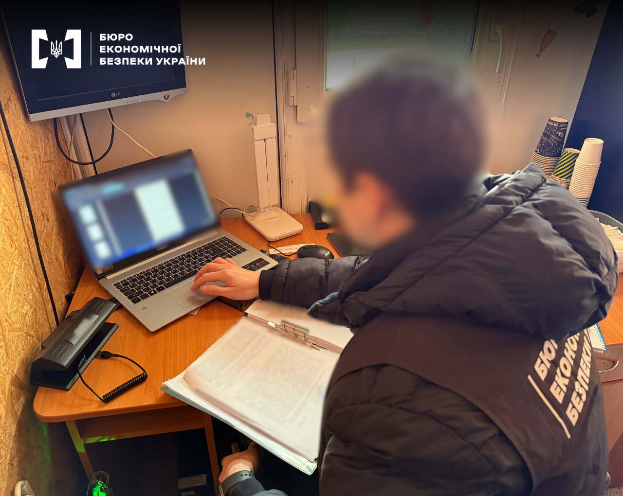 Слідчі дії. Детектив БЕБ перевіряє дані в ноутбуці та працює з документами в робочому кабінеті АЗС. 