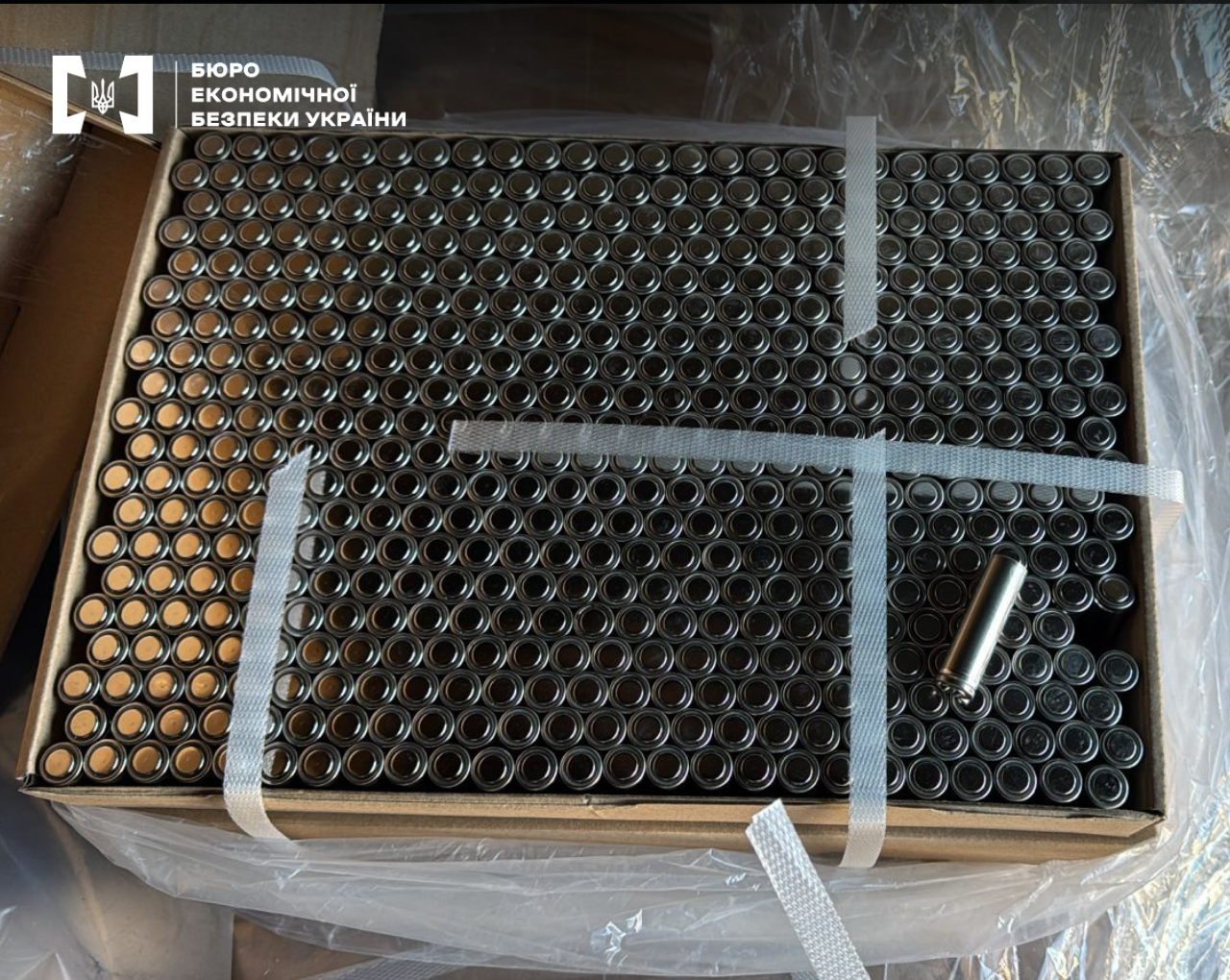 A cardboard box filled with round metal batteries.
