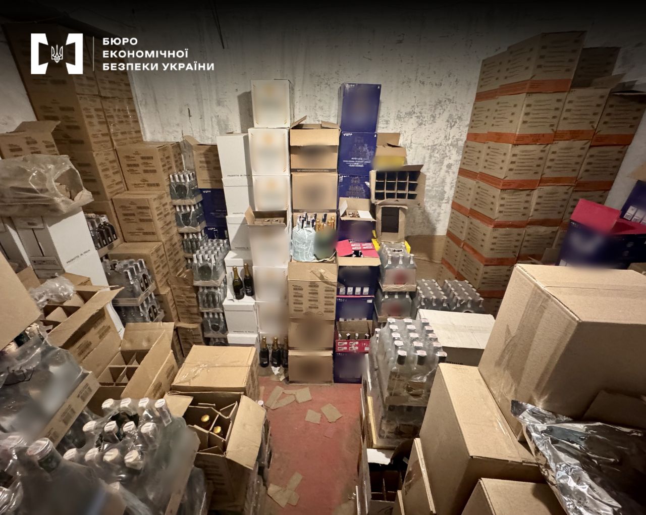 A warehouse facility filled to the ceiling with boxes of alcoholic beverages. Cases of vodka, wine, and sparkling wines are visible