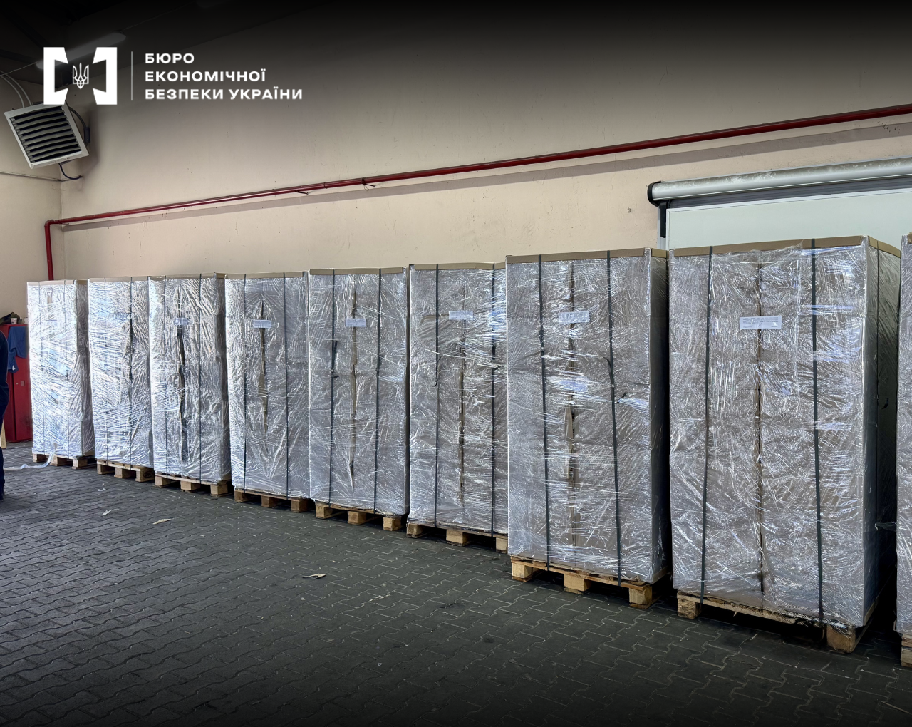 A row of large cargo pallets with boxes wrapped in clear stretch film in a warehouse.