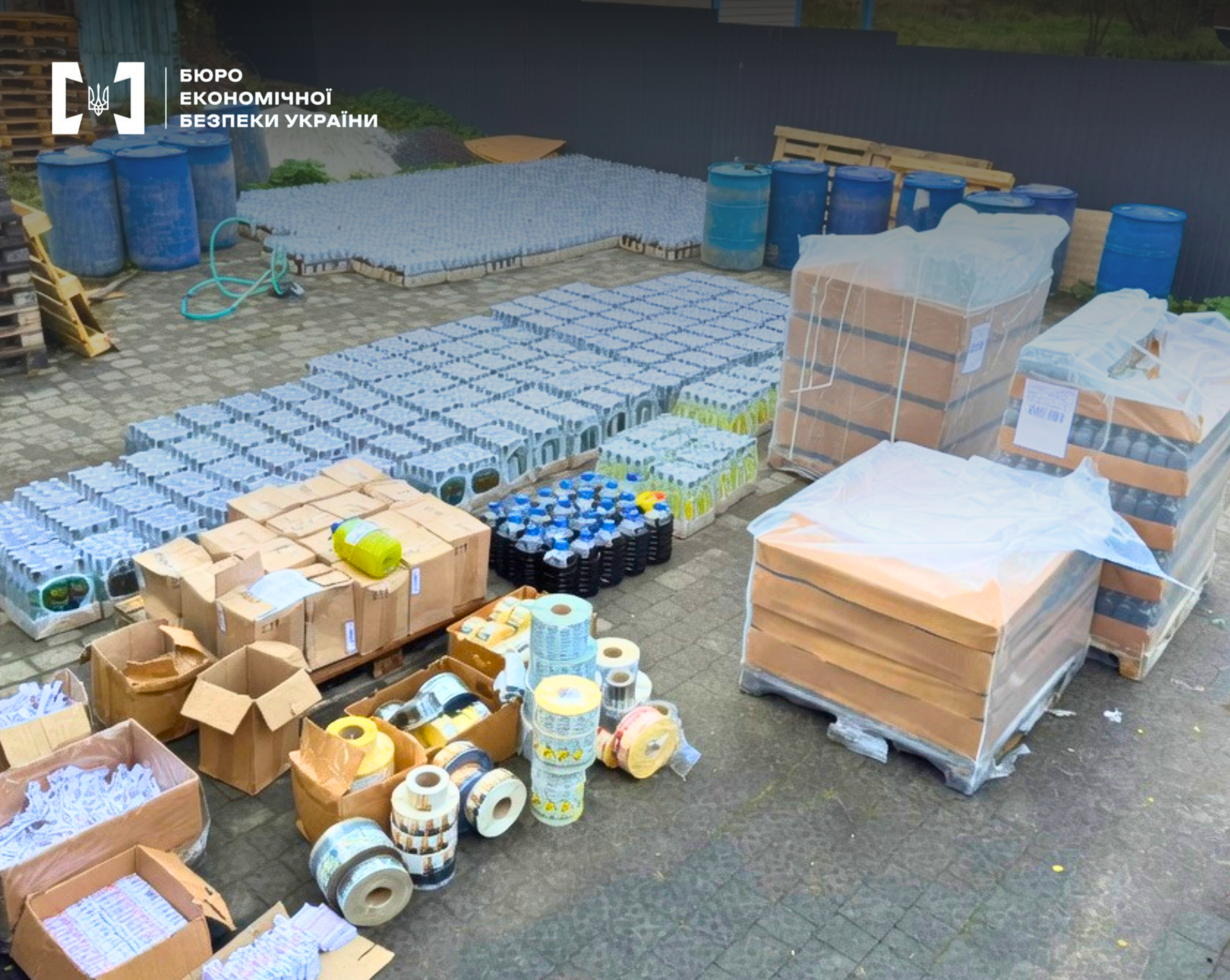 A large number of glass bottles in packs, cardboard boxes, and rolls of stickers on the paving stones.