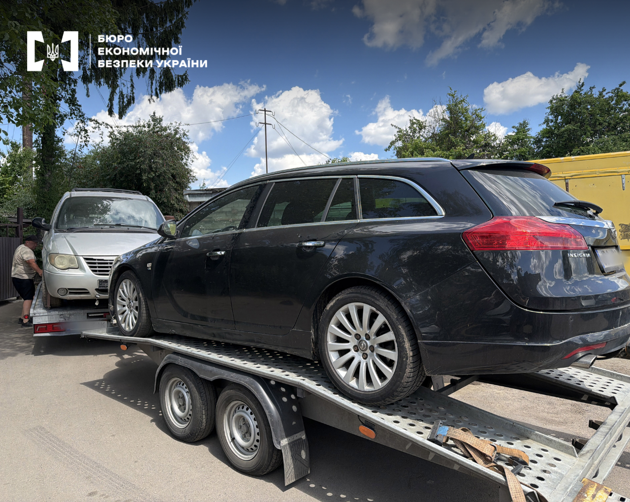 Transportation of two passenger cars on a towing platform during the day.