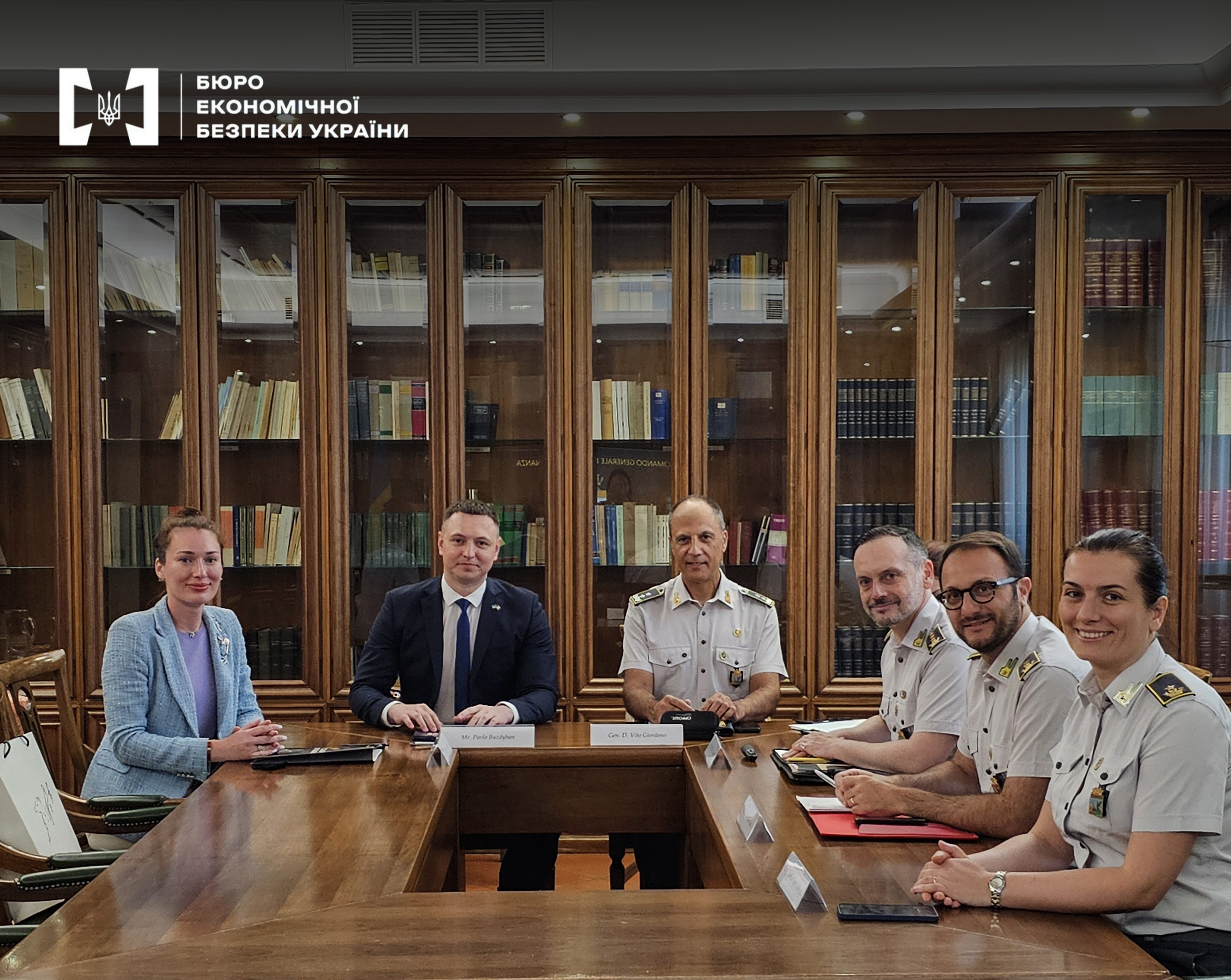 Official meeting of the ESBU delegation and the Italian Financial Guard at a large wooden table against the background of bookcases.