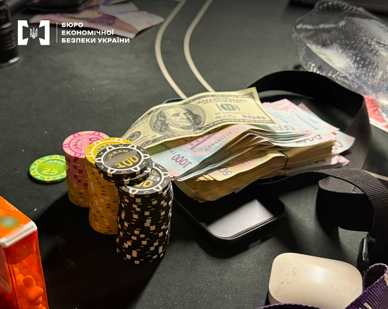 Packs of US dollars and hryvnias next to tall stacks of poker chips on a table.