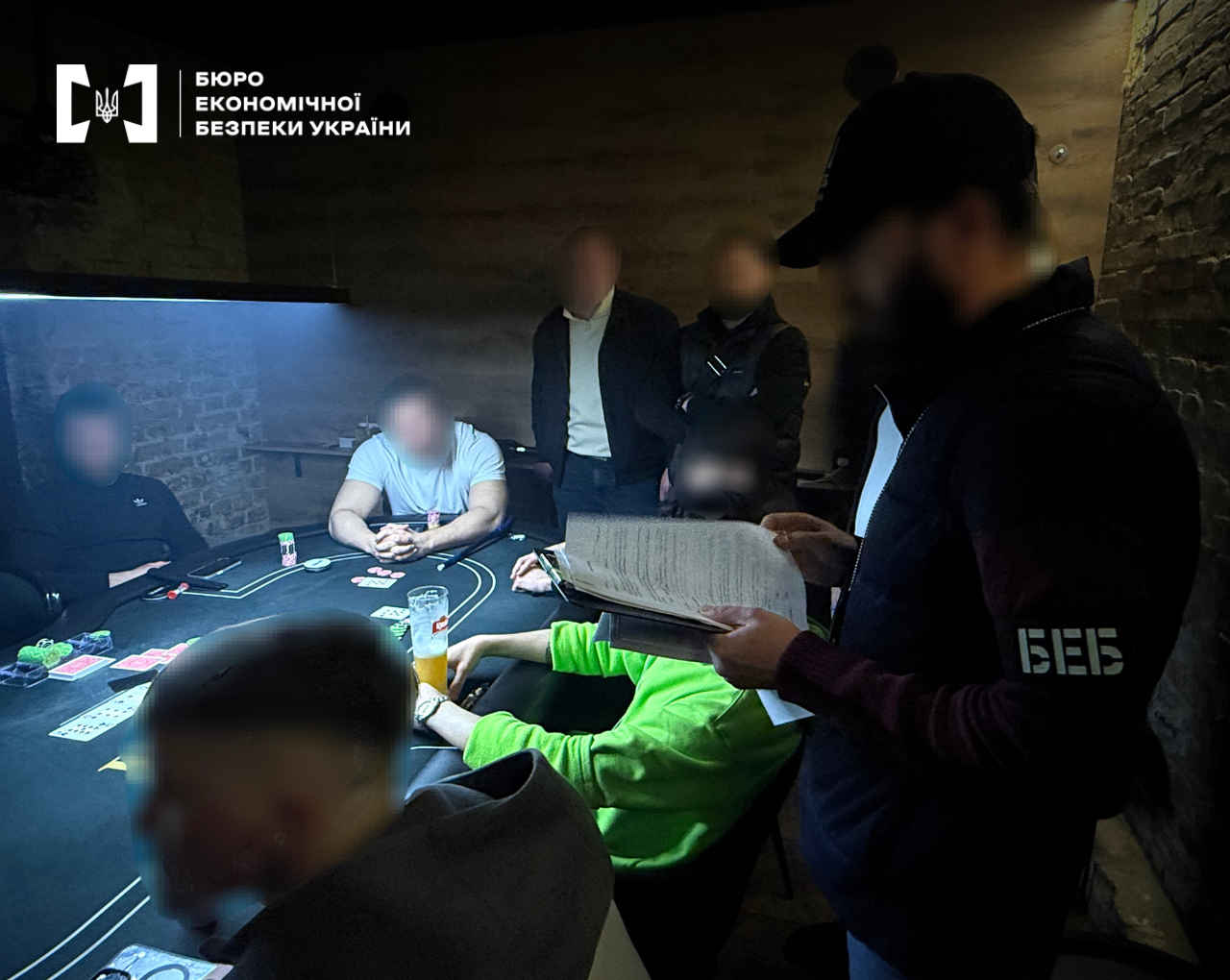An ESBU detective reads out documents during a search of an underground casino at a poker table.