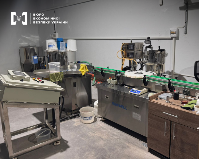 An e-liquid production workshop. A control panel, an automated line for filling and packaging liquids, and plastic buckets are visible.