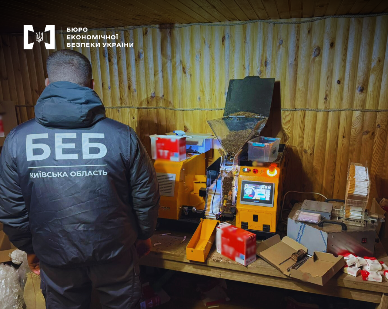 An ESBU detective is conducting a search at an illegal tobacco manufacturing facility. The frame shows a cigarette-stuffing machine in operation