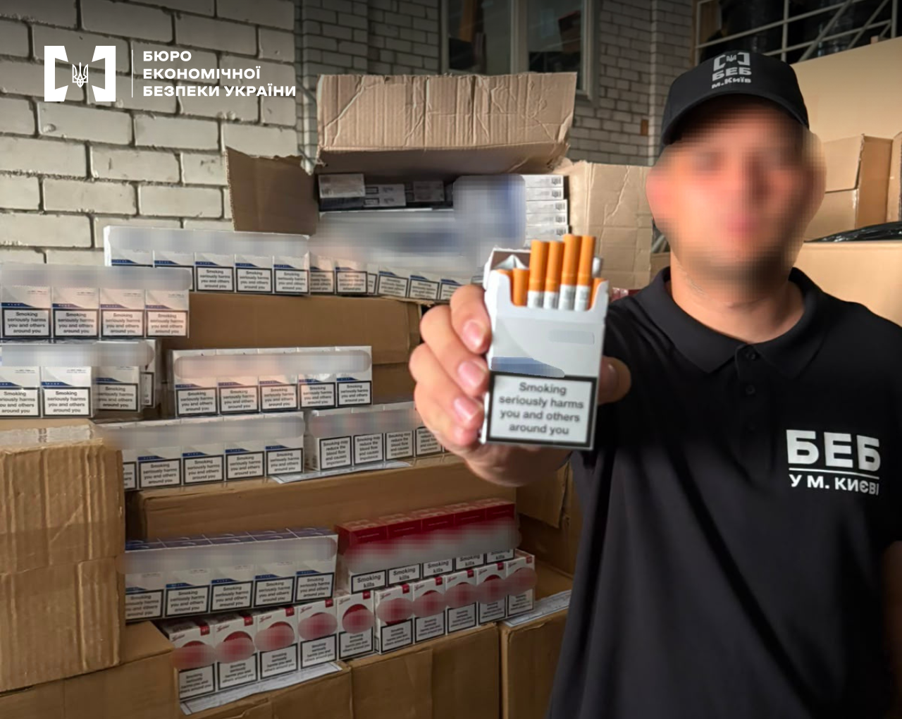 An ESBU detective shows an open pack of cigarettes with the English warning 'Smoking seriously harms you...' against the background of a warehouse.