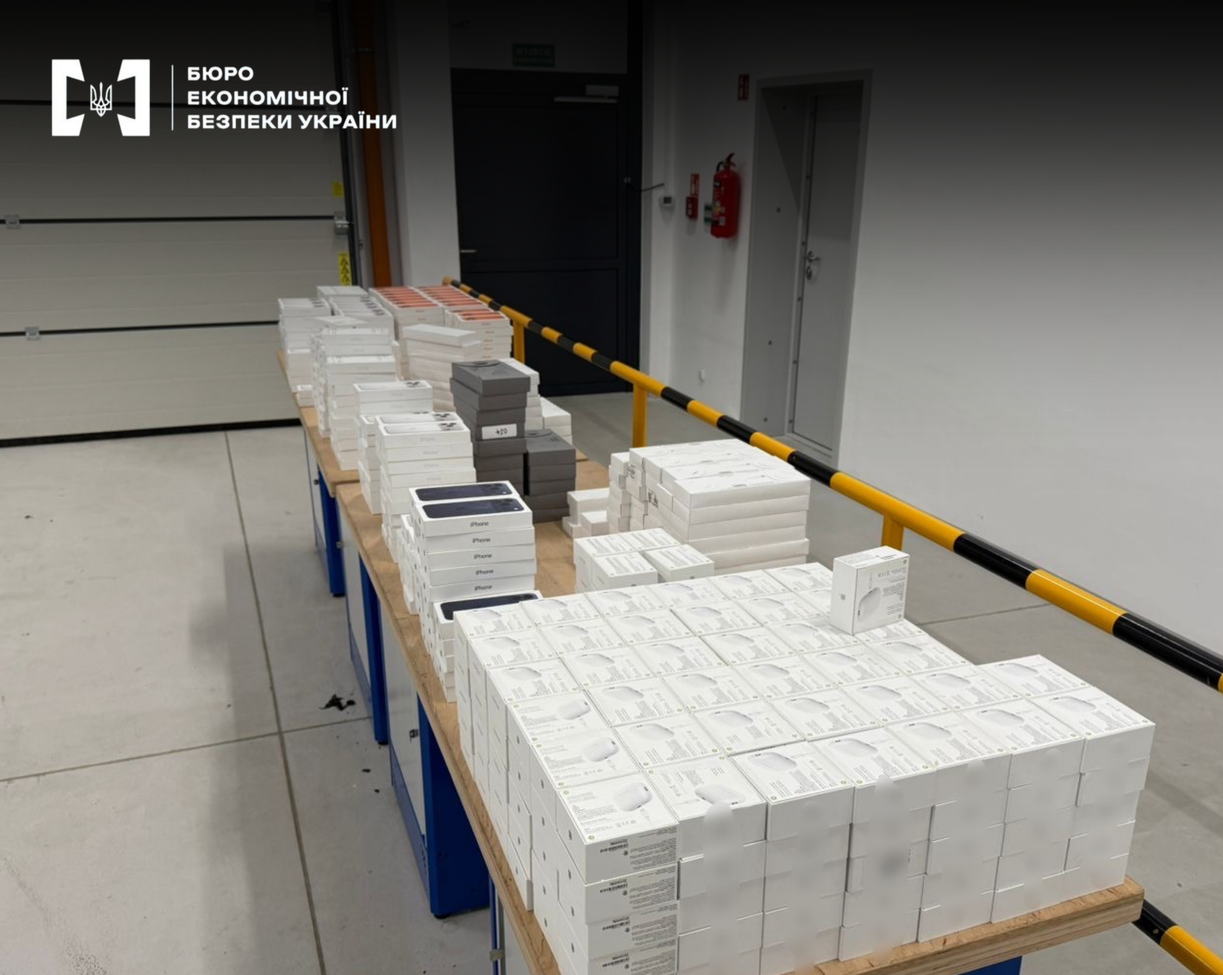 A large batch of seized Apple equipment, iPhone smartphones, and accessories in boxes on a table.