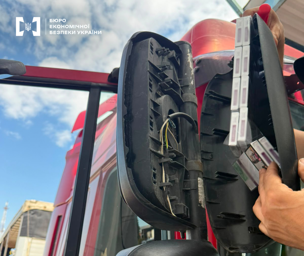 Smuggled cigarettes hidden inside the disassembled side mirror of a red truck.