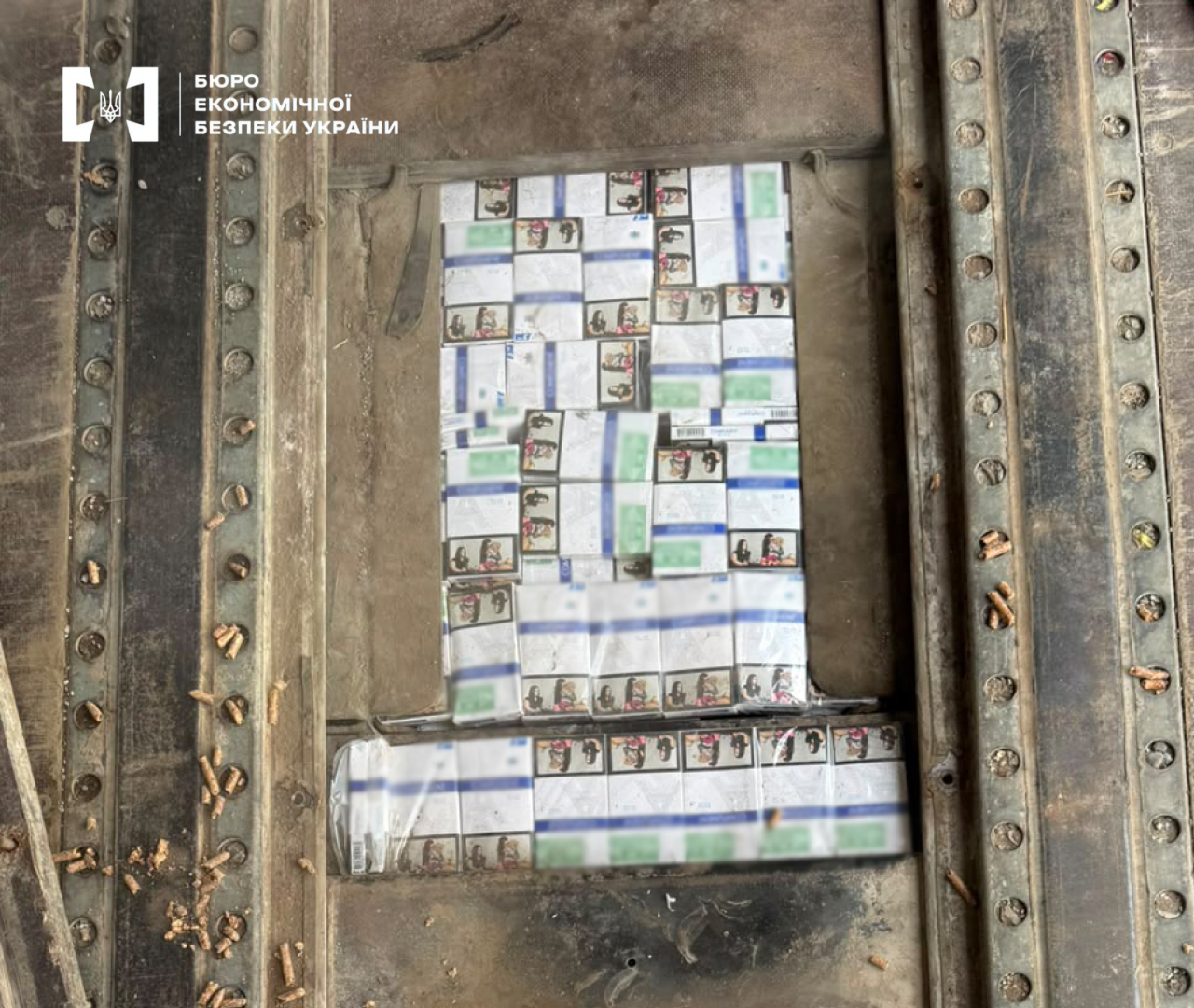 Cartons of cigarettes without Ukrainian excise stamps with foreign health warnings in a hidden vehicle compartment.